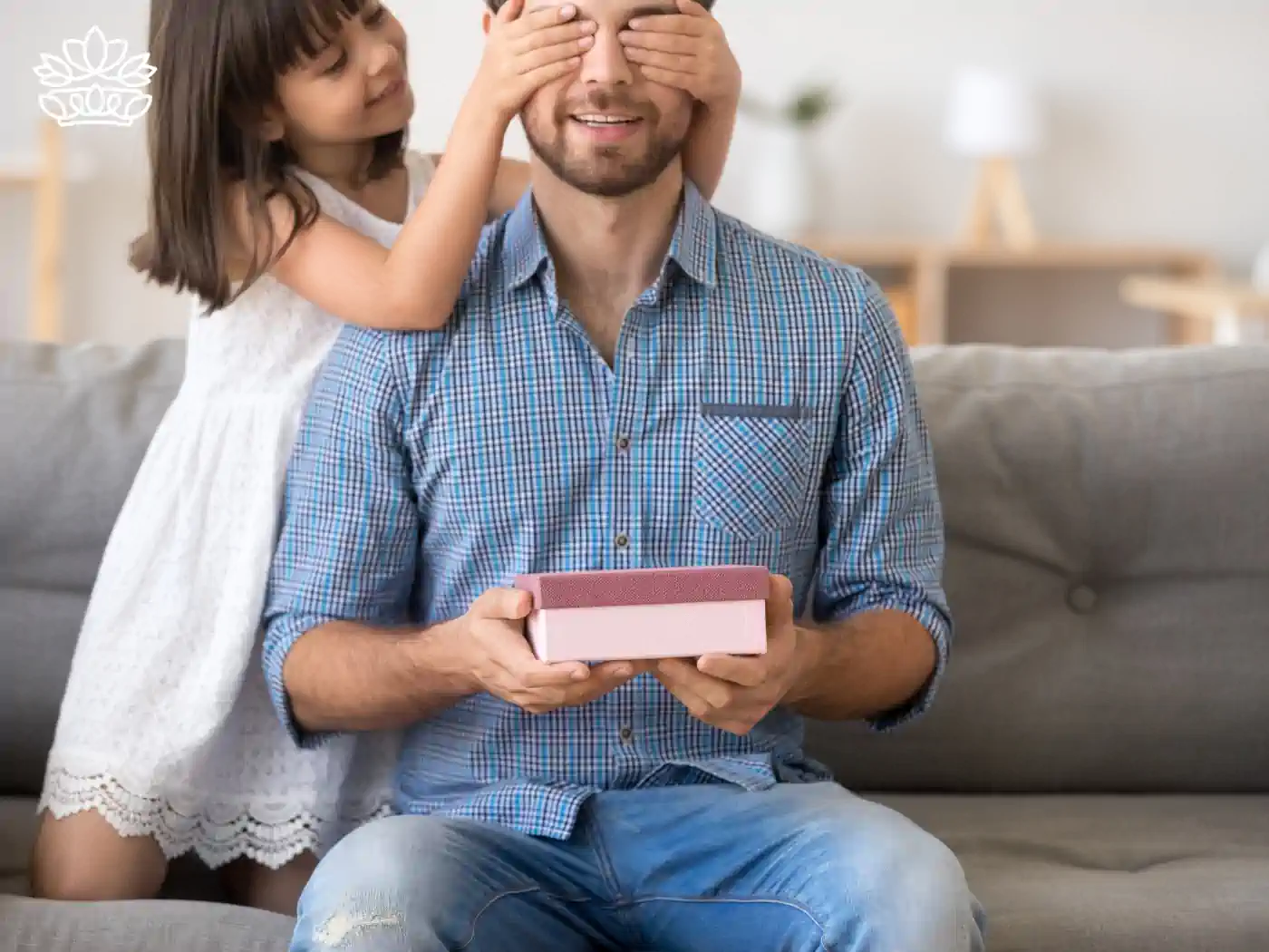 A little girl surprising her father with a gift box while covering his eyes - Fabulous Flowers and Gifts - Nationwide Gift Box Delivery