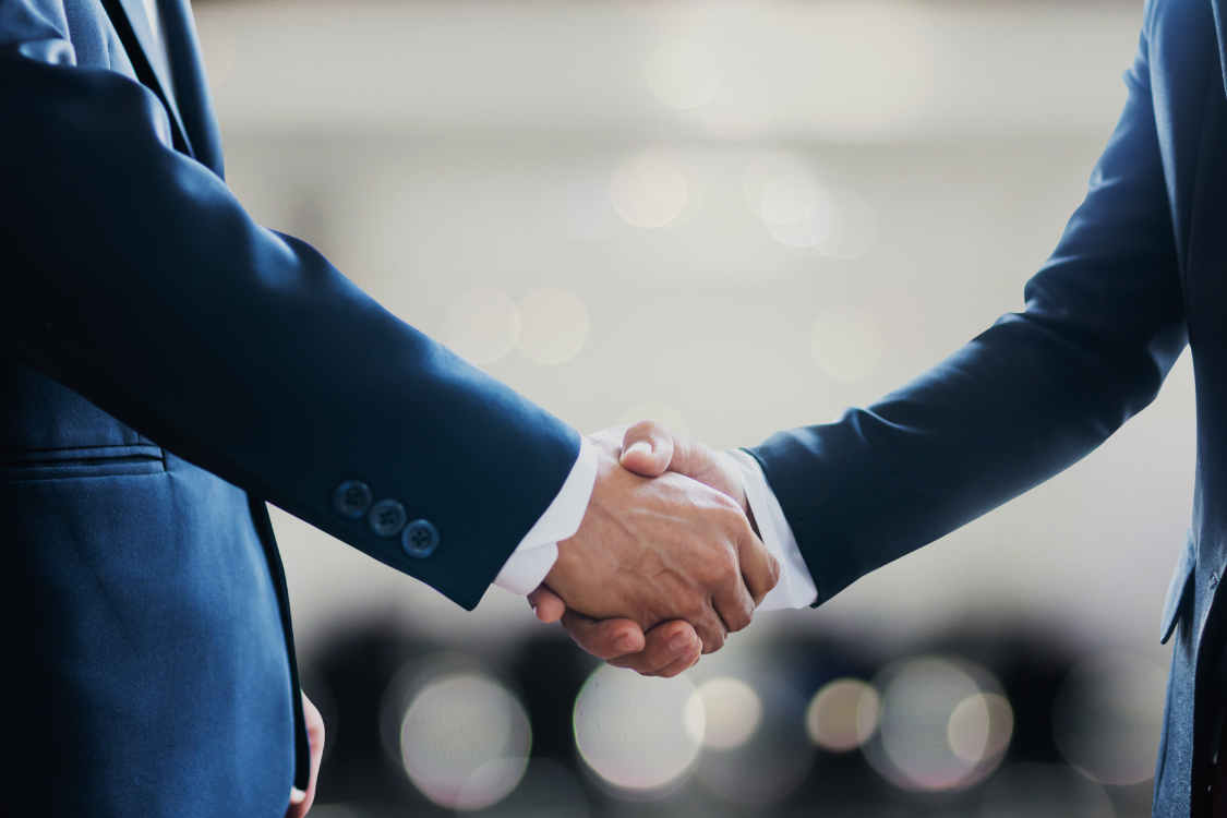 Two business professionals shaking hands during a business sale agreement without a broker
