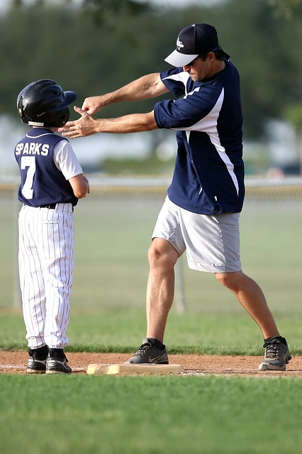 Little League player with a little league coach giving instruction.