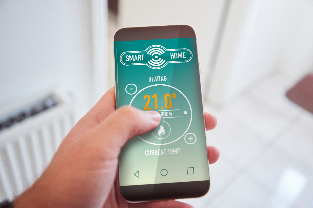 Iemand gebruikt een smart home app op zijn telefoon om de verwarming te regelen