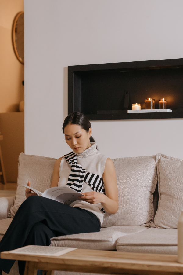a woman from a marketing team reading a magazine indoors on a sofa; she could be in New York, Canada, or anywhere in between