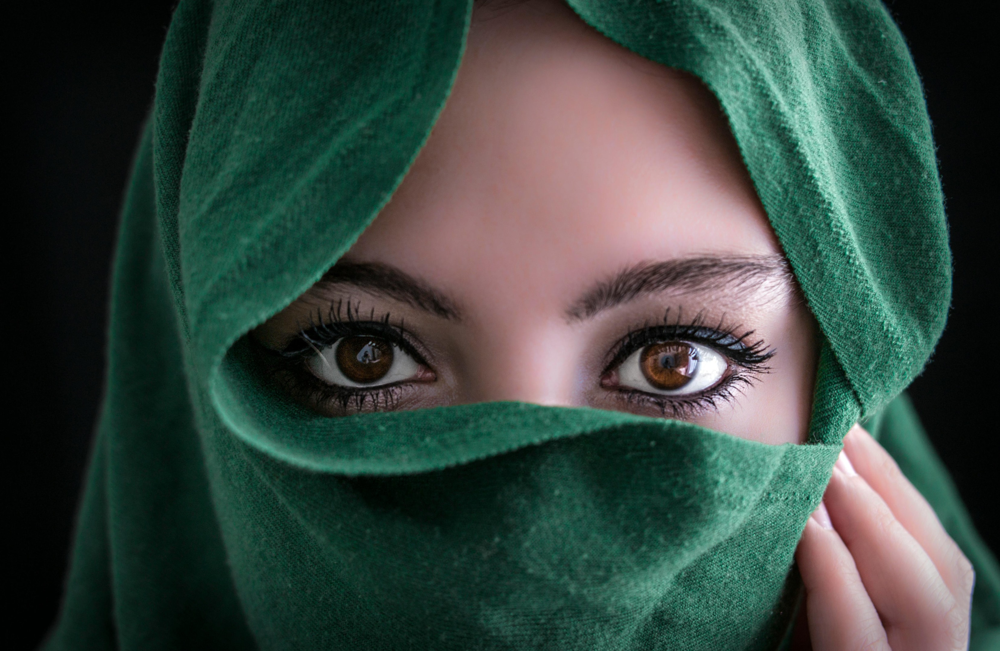 Closeup of a hijabi covering her lower face with her green hijab