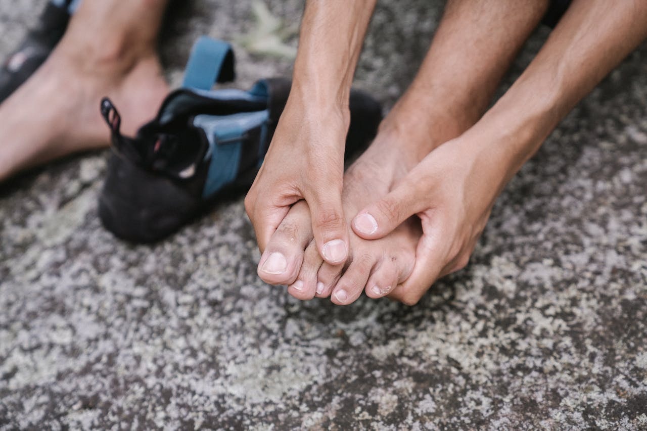 Close-up of a person holding sore toes after wearing tight shoes, showing foot pain and pressure near the forefoot.