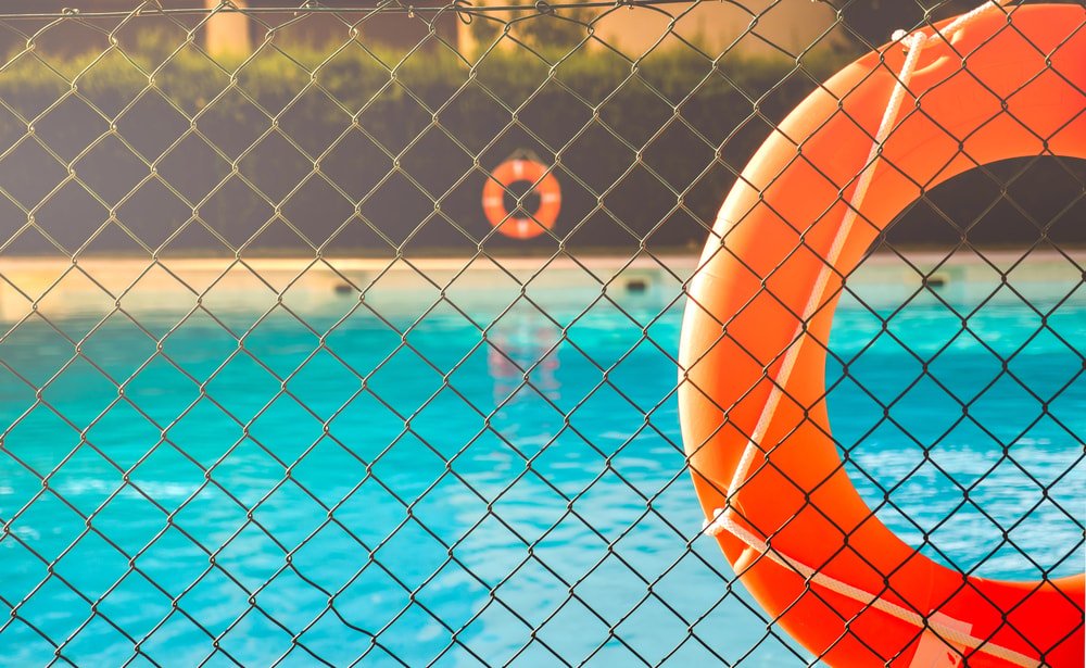 Pool safety fence in Florida surrounding a residential swimming pool with a life ring for added protection.