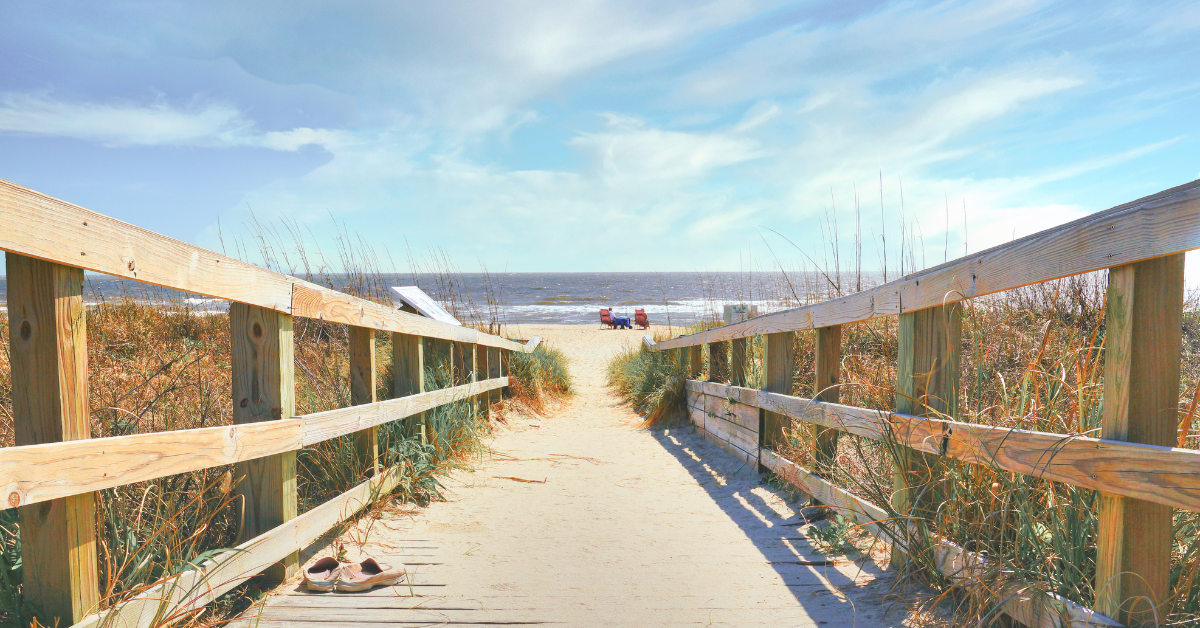 Wooden boardwalk leading to the sandy beach in Bay Head NJ, with chairs set up by the ocean for a relaxing Jersey Shore getaway.