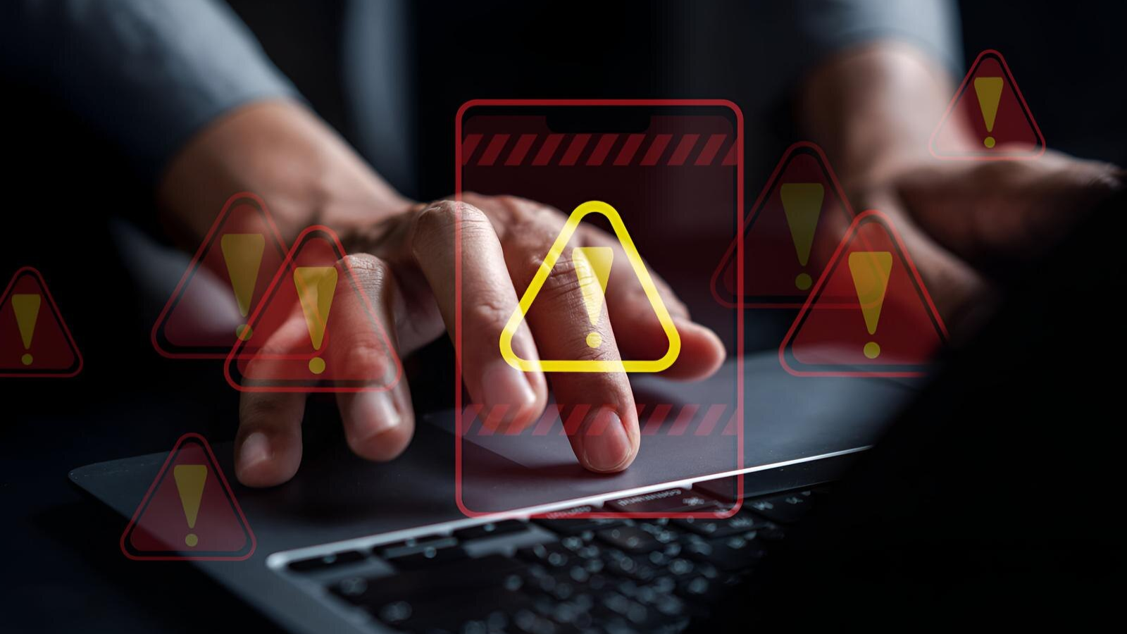 Hands typing on a laptop keyboard overlaid with digital red and yellow warning icons, visually representing telecom outages and how cloud PBX solutions offer automatic call failover and reliable business continuity features.
