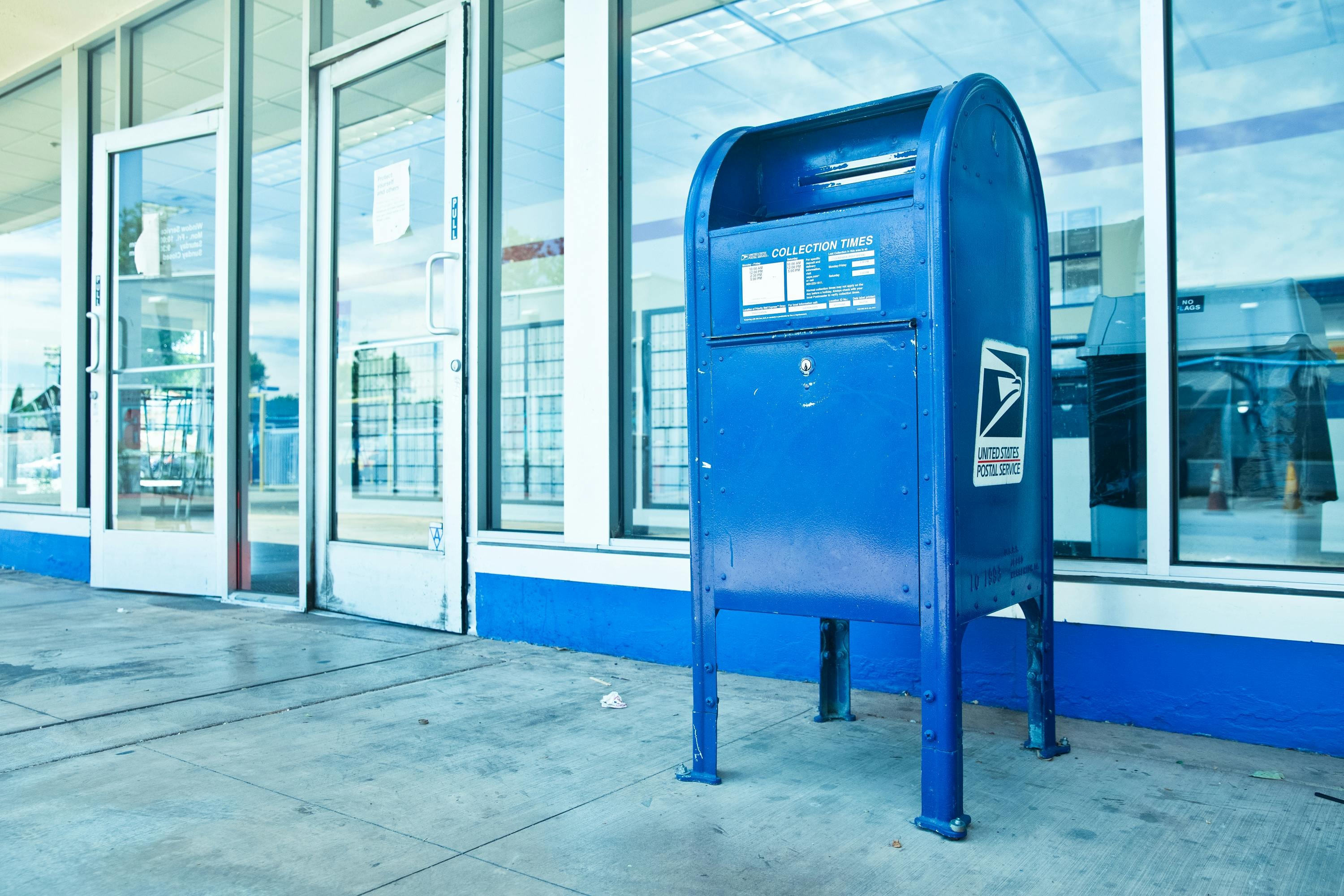 Blue USPS mailbox in front of a business. 