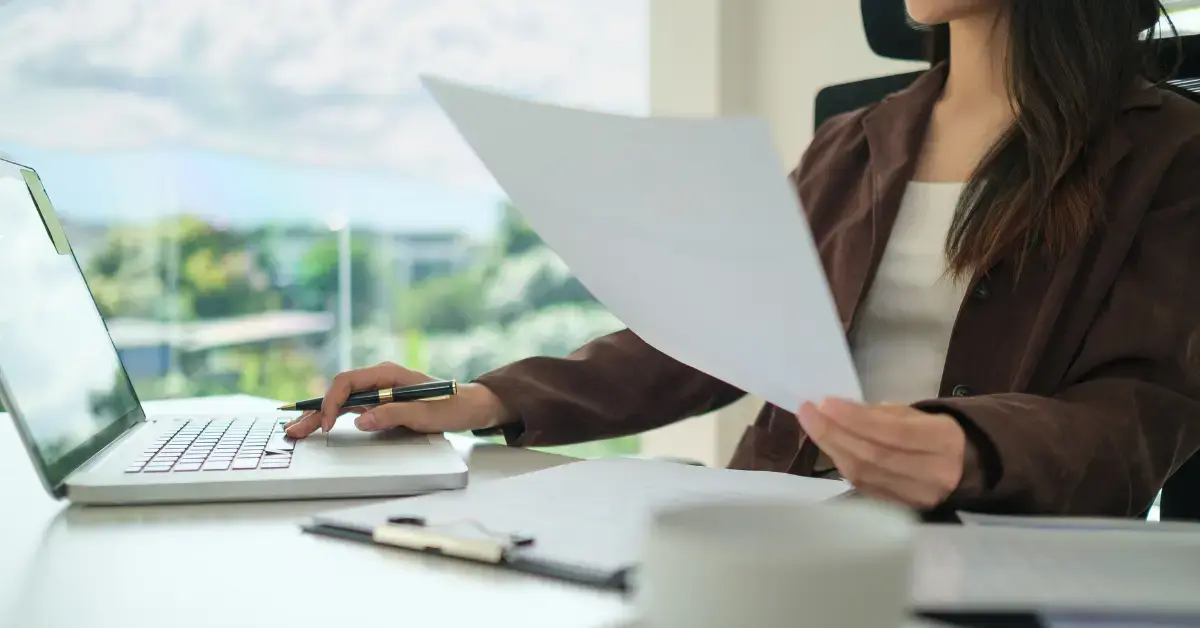 Woman reviewing IRS Notice CP23 and estimated tax payment records at her desk.