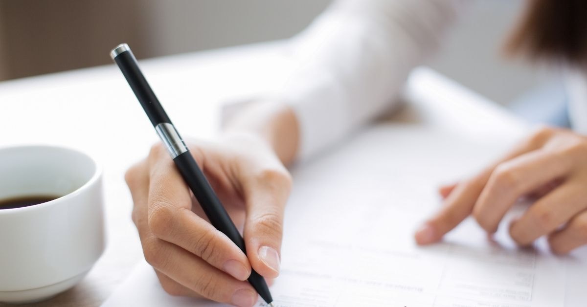 Close-up of a person filling out an empty W-9 form with a pen.