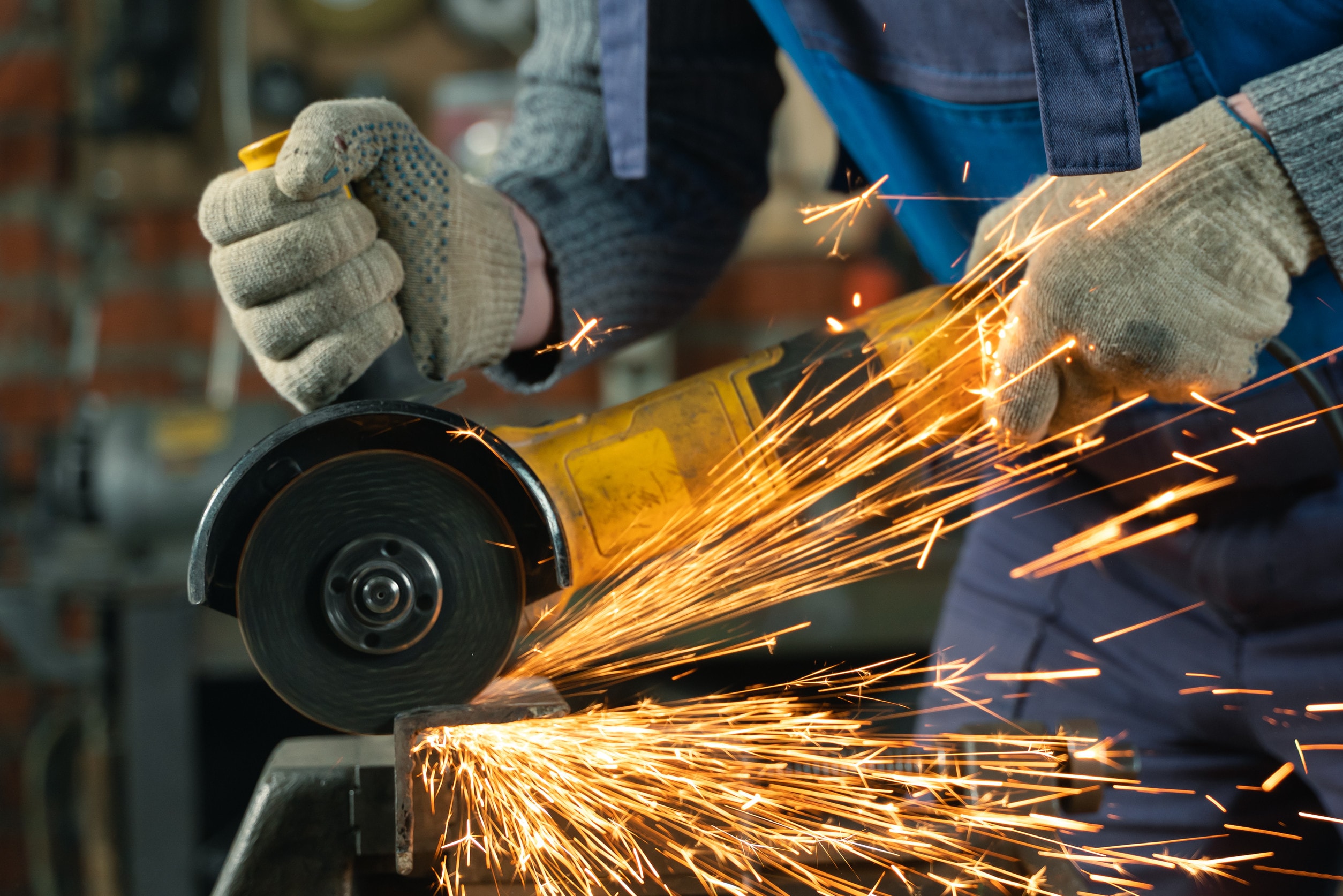 A common cause of factory machinery accidents, a saw, causes sparks to fly onto a worker.