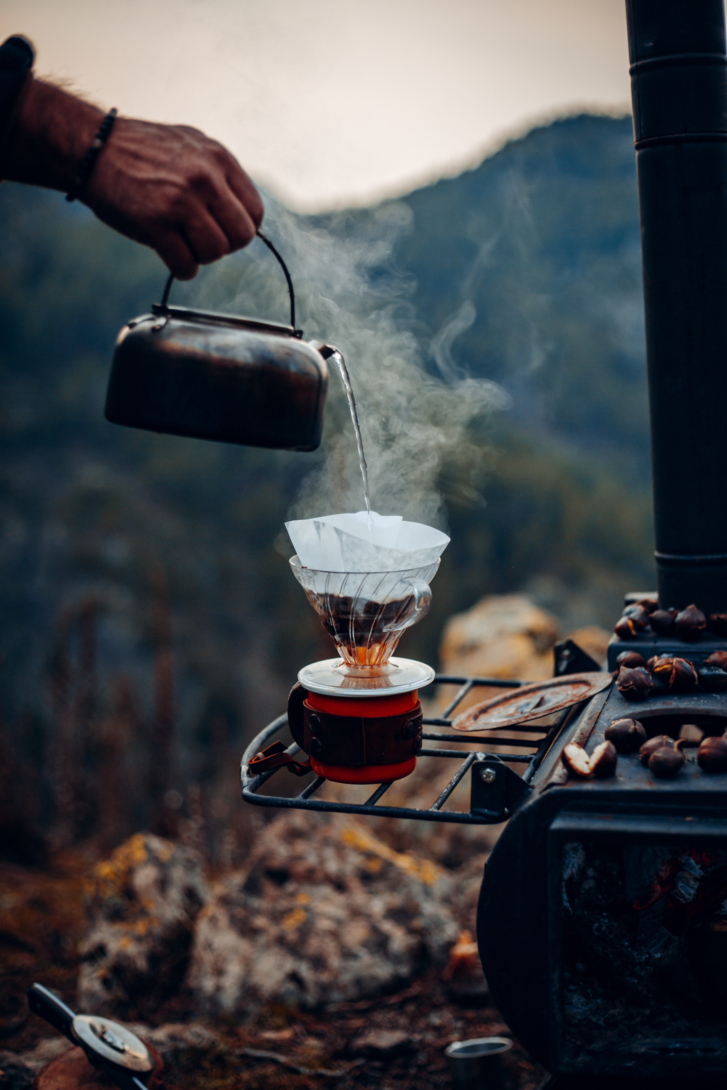 man making pour over joe while camping in the mountains