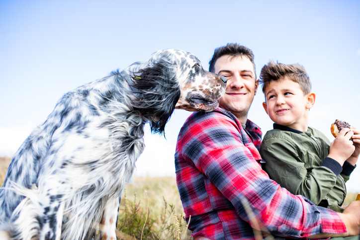 Happy dad and son outside with their dog. 