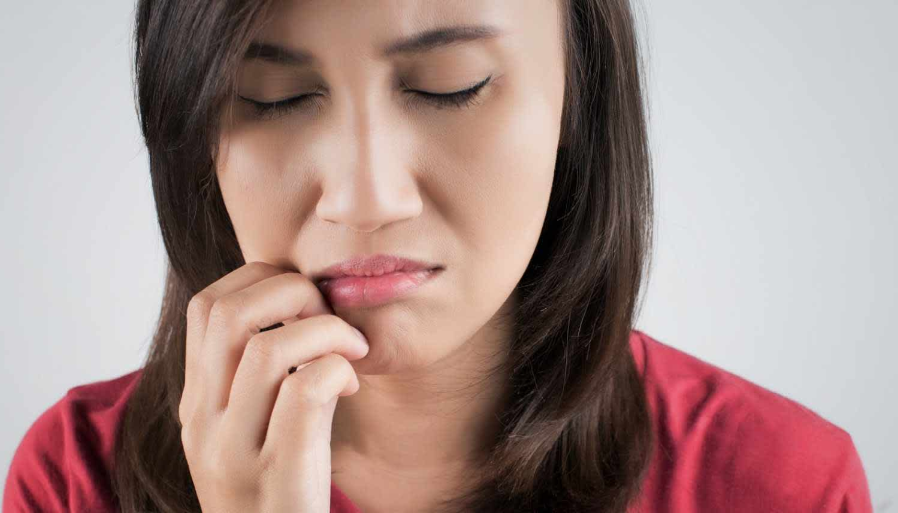 "Kvinne med smerteuttrykk holder hånden mot munnen, antyder tannpine eller ubehag i kjeven."
