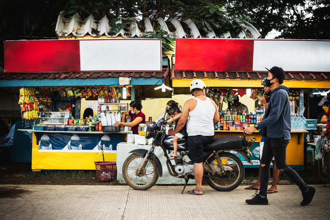 Filipino vendor and customers at a local street stall representing regional living costs