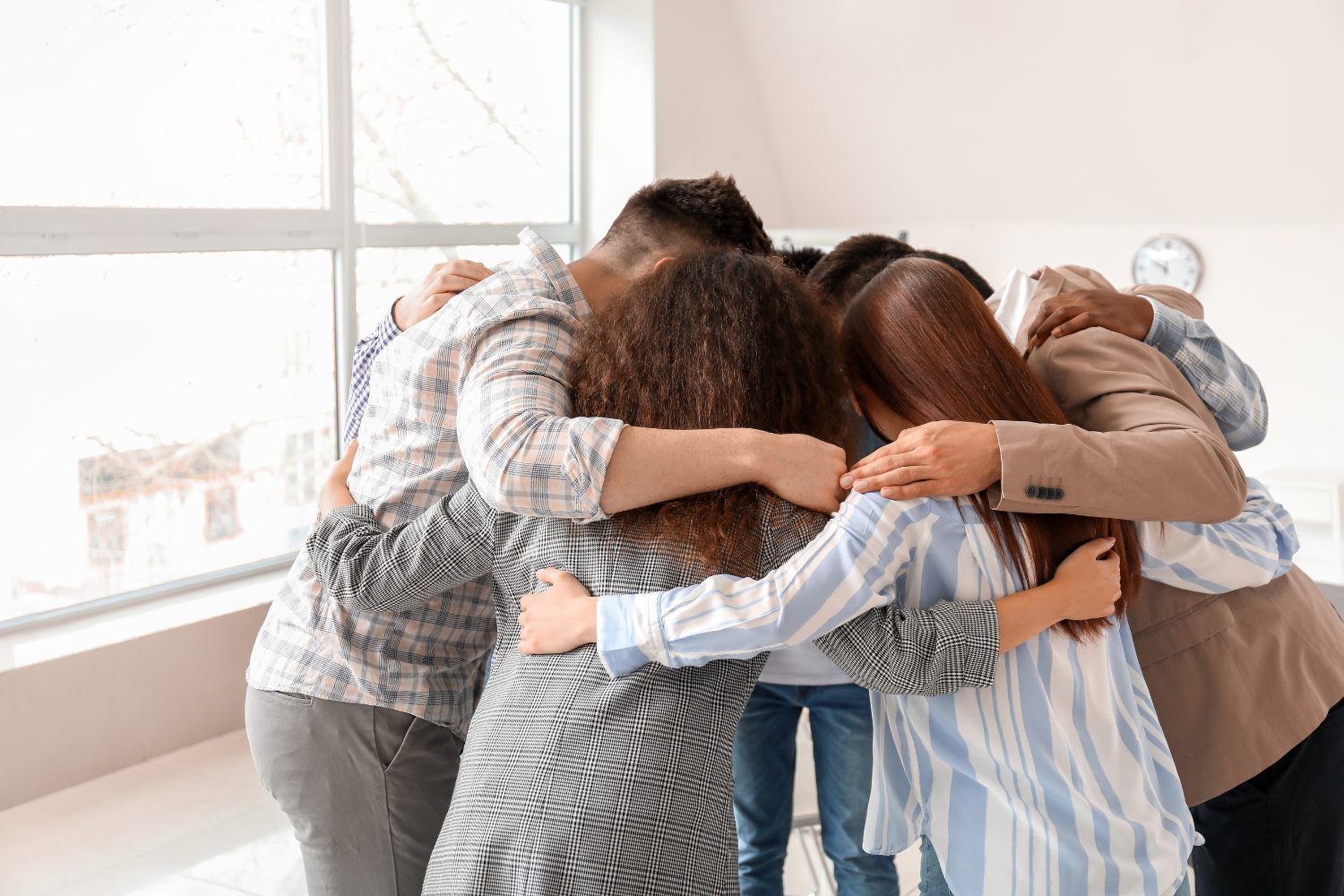 A team with arms around each other in a group hug.
