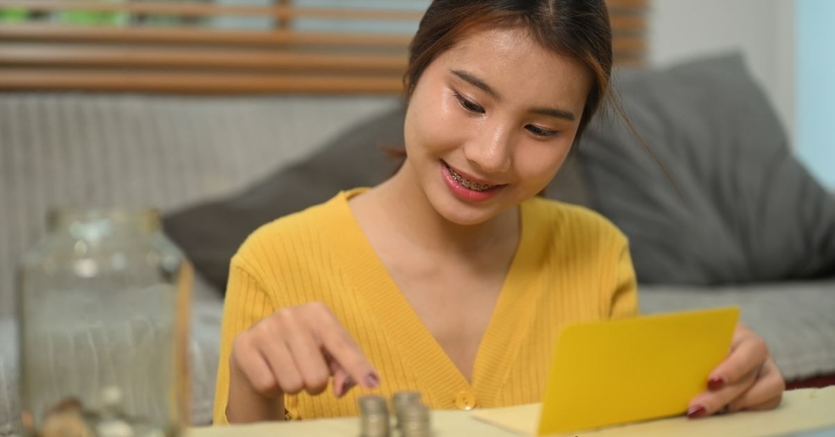 A young woman being financially responsible by counting coins and managing her savings at home.