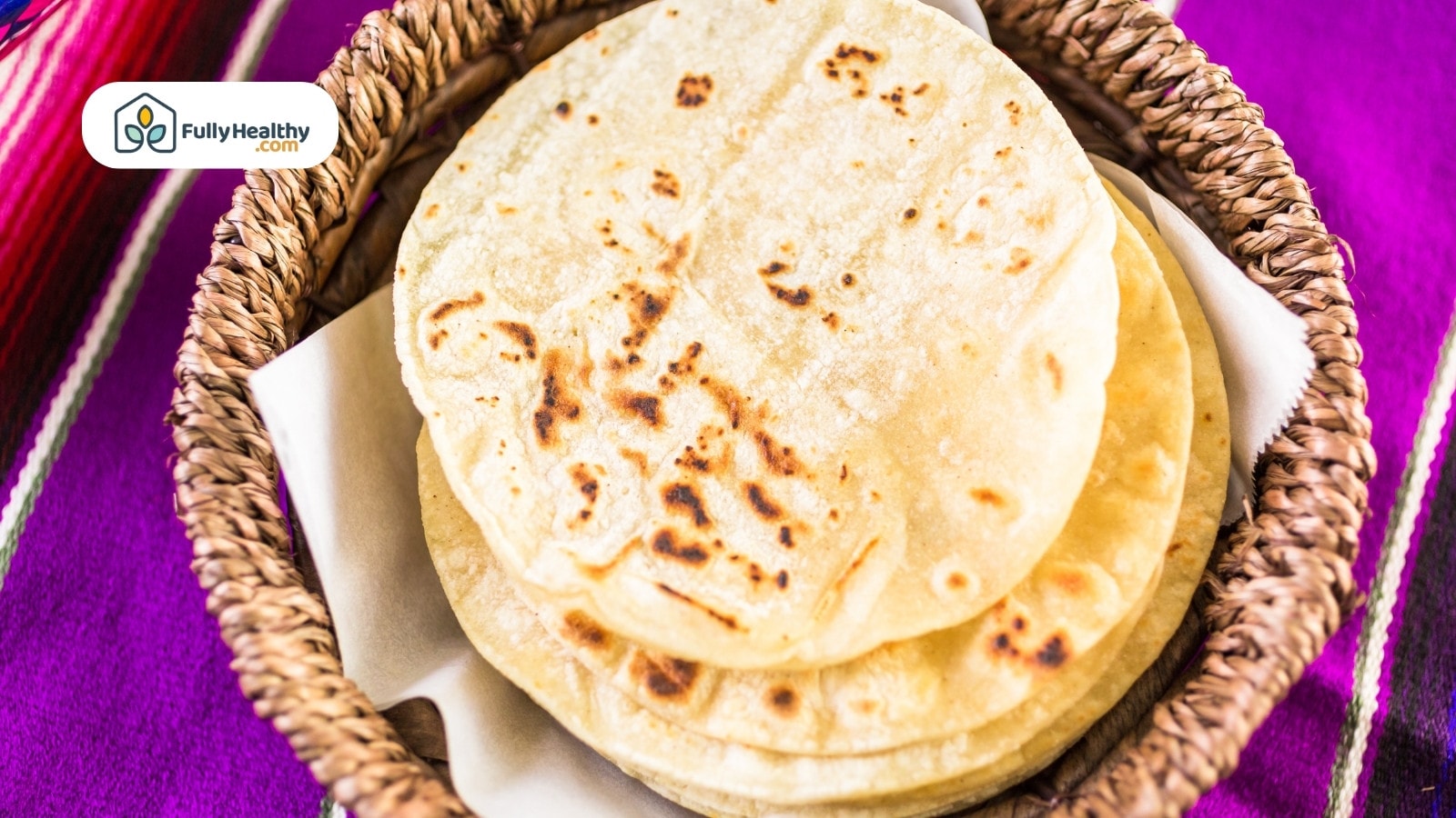 Freshly made tortillas stacked in a woven basket.