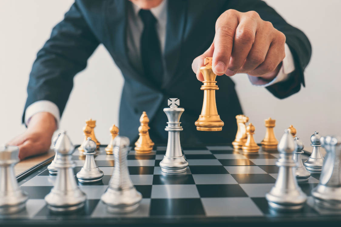 Businessperson moving a golden king chess piece on a board, symbolizing strategic deal-making in M&A