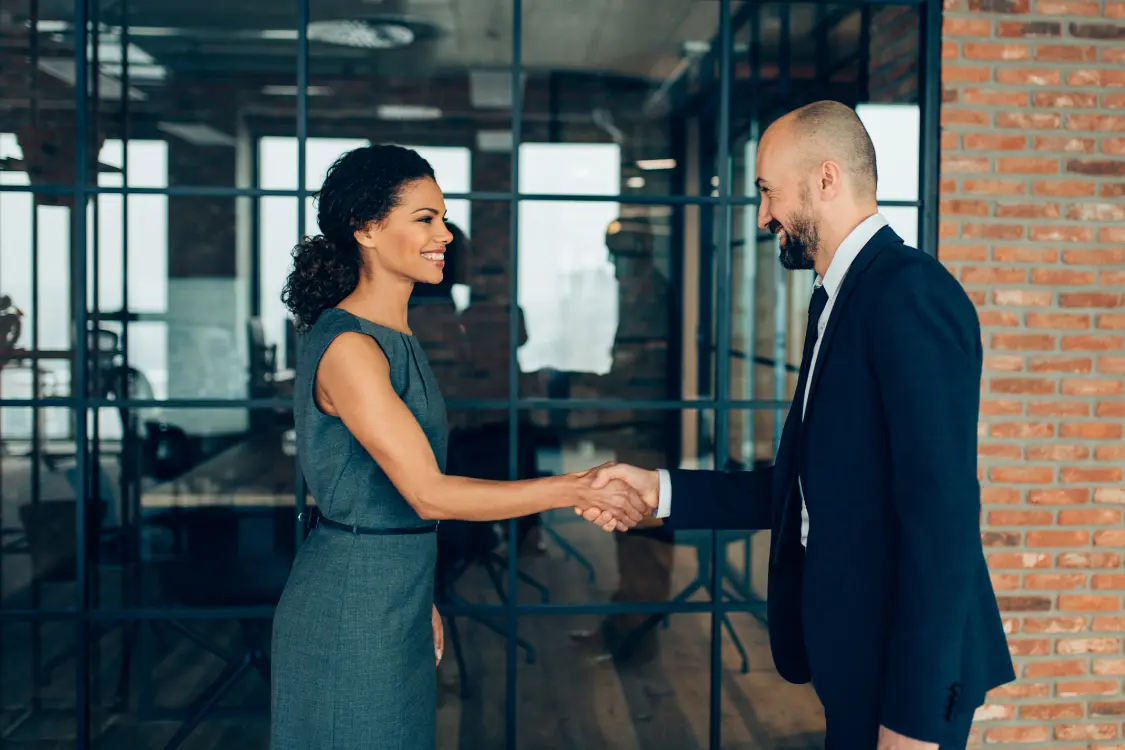 Business broker shaking hands with a client in a modern office