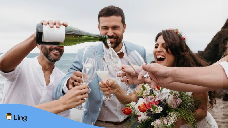 A photo of a newlywed couple pouring champagne in glasses, an occasion to say cheers in Bosnian.