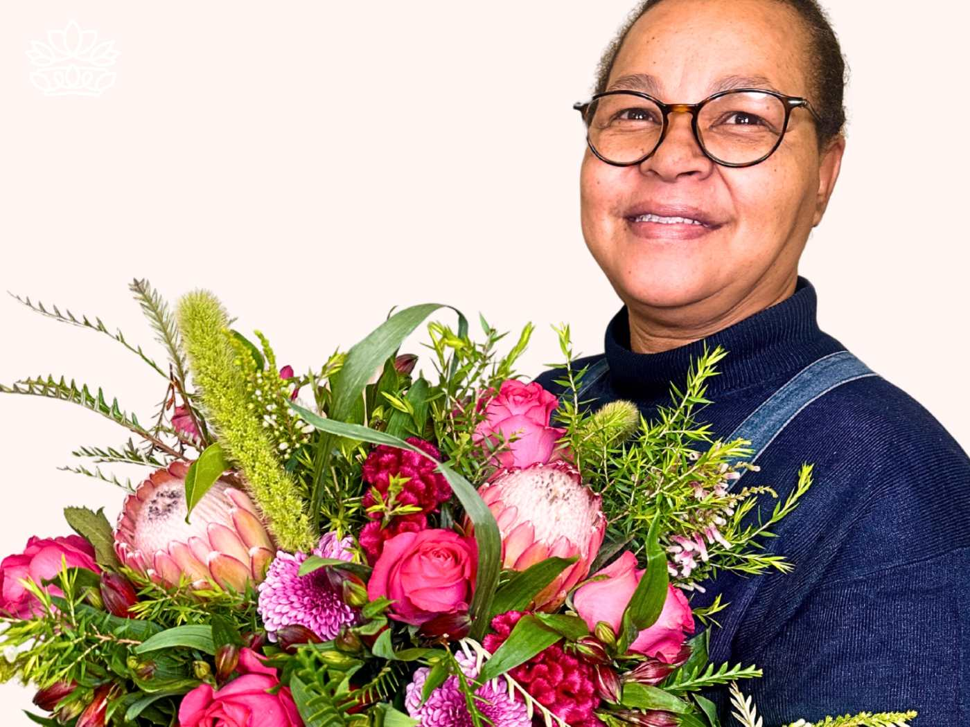 Smiling florist holding a vibrant bouquet from the Florist Choice Bouquets Collection, featuring a mix of pink roses, proteas, and lush greenery, showcasing expertise and craftsmanship. Fabulous Flowers and Gifts.