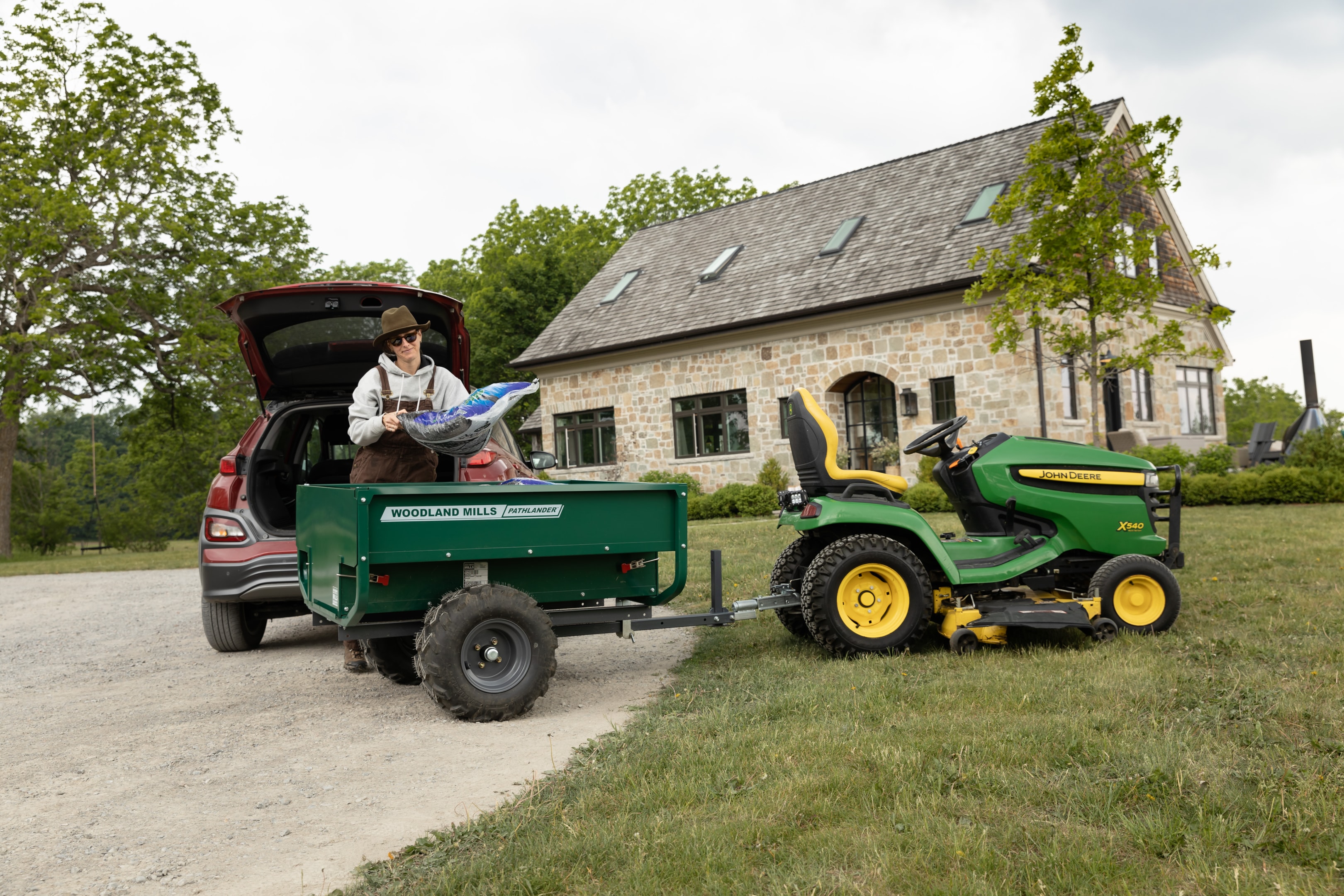 La remorque Pathlander de Woodland Mills, attelée à une tondeuse à gazon via un attelage à boule. 