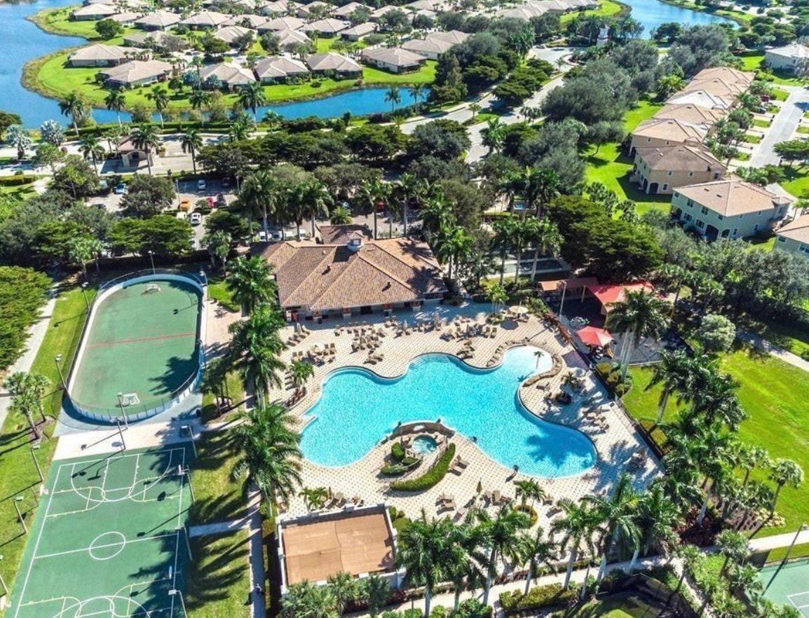 The image depicts a resort-style pool featuring elegant waterfall elements, surrounded by lush palm trees and Mediterranean-style architecture, showcasing the luxurious amenities of the Bella Terra community in Estero, FL. This serene setting highlights the inviting atmosphere of the neighborhood, perfect for relaxation and leisure.