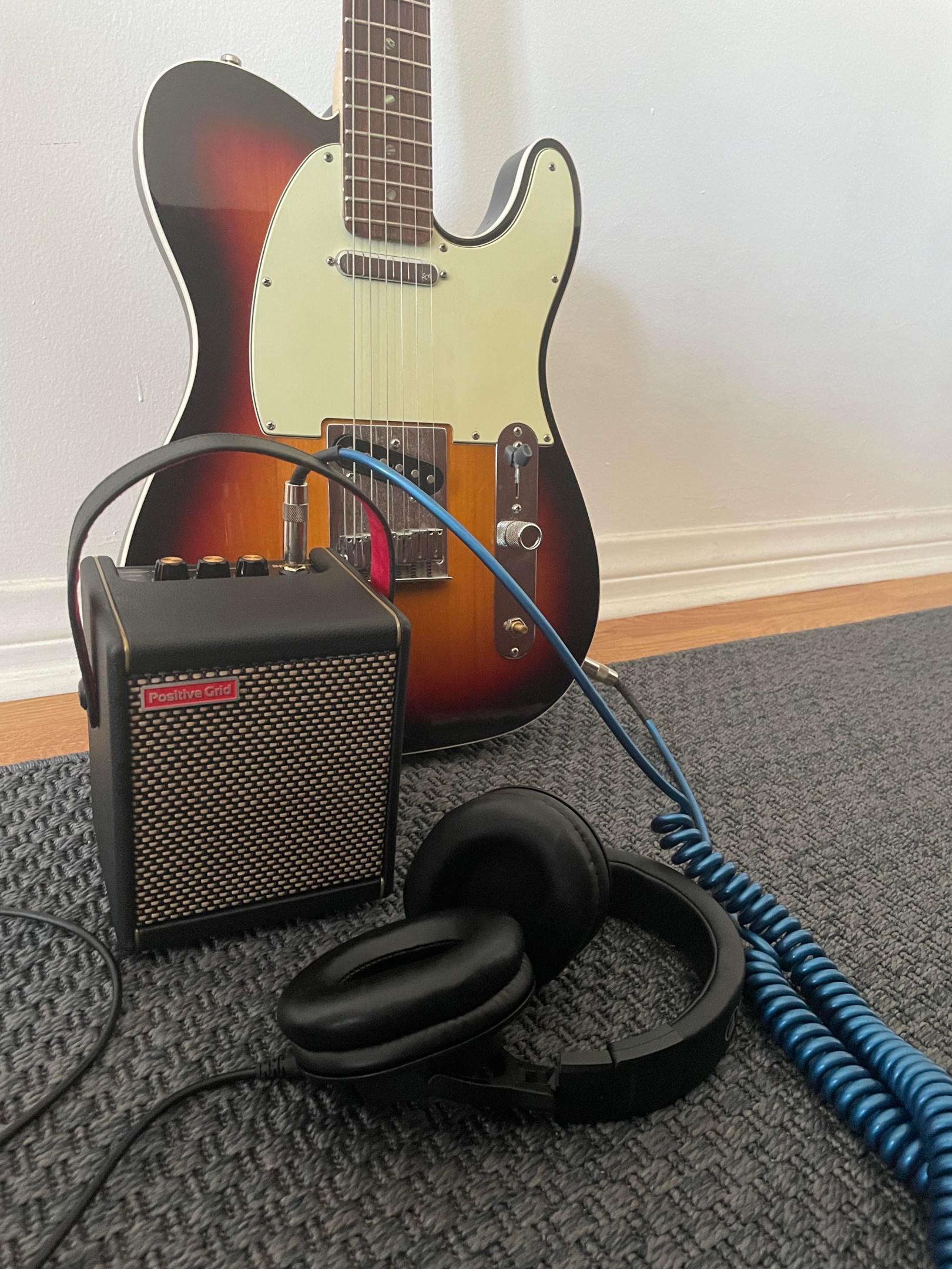 A Positive Grid Spark Mini amp with headphones and guitar.