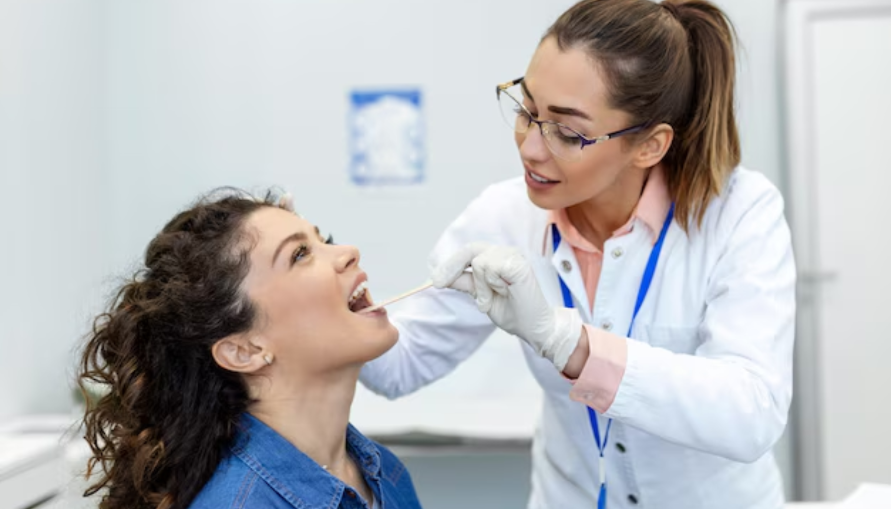 Blåtunge: Når Fargen Forteller Mer Enn Du Skulle Tro 14 Lege undersøker halsen til pasient med trepinne under kontrollert lys i et klinisk miljø med fokus på munnhulen.