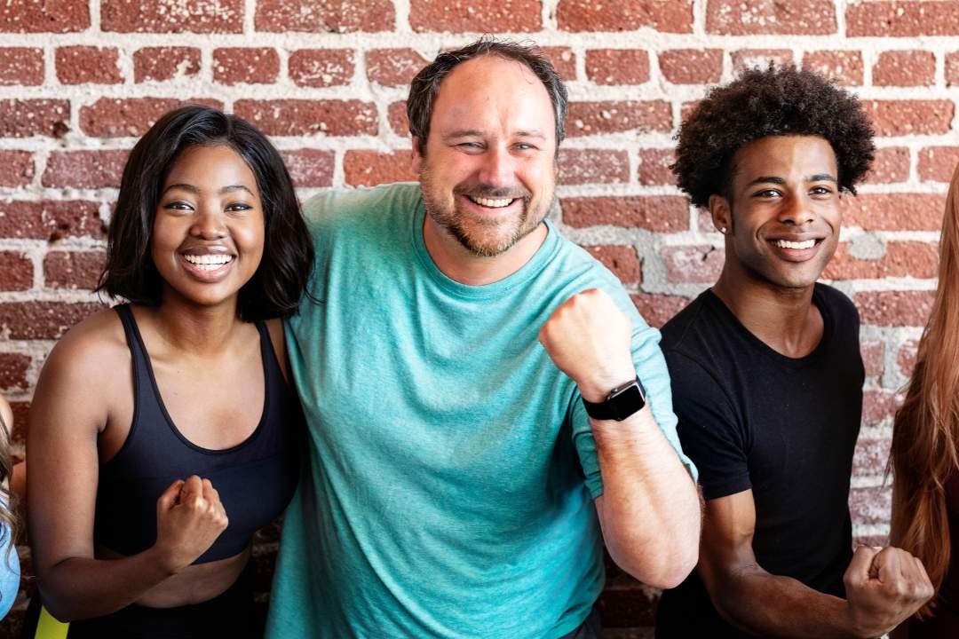 A close-up of three smiling individuals with fists raised, showing camaraderie and a fun, active atmosphere.