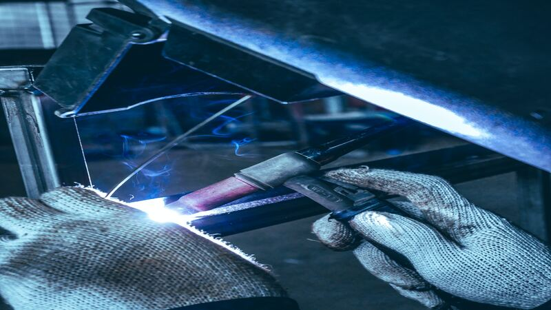 A welder focusing on welding by positioning the componets of the frame in a welding fixture. 