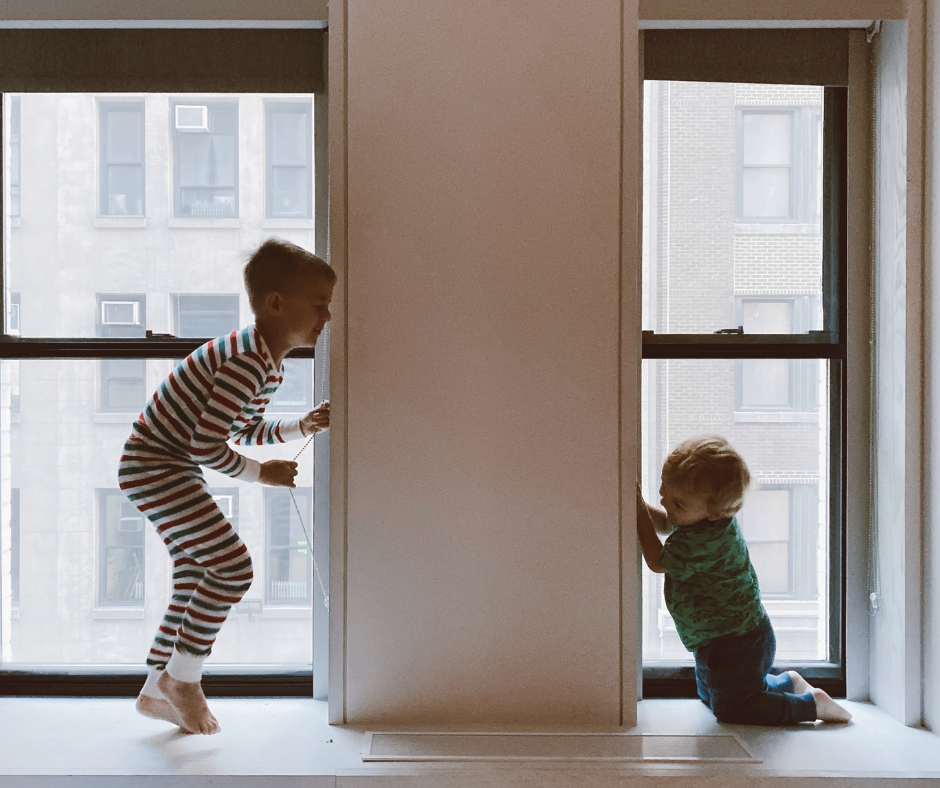 a boy hides from a new baby behind a window