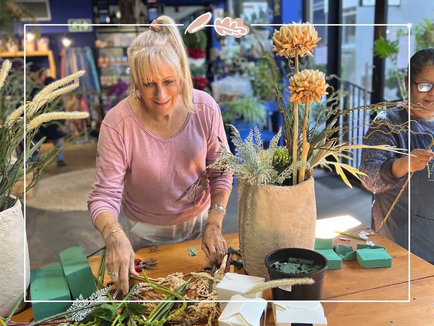 Florist arranging diverse dried and fresh flowers in a creative workshop setting.