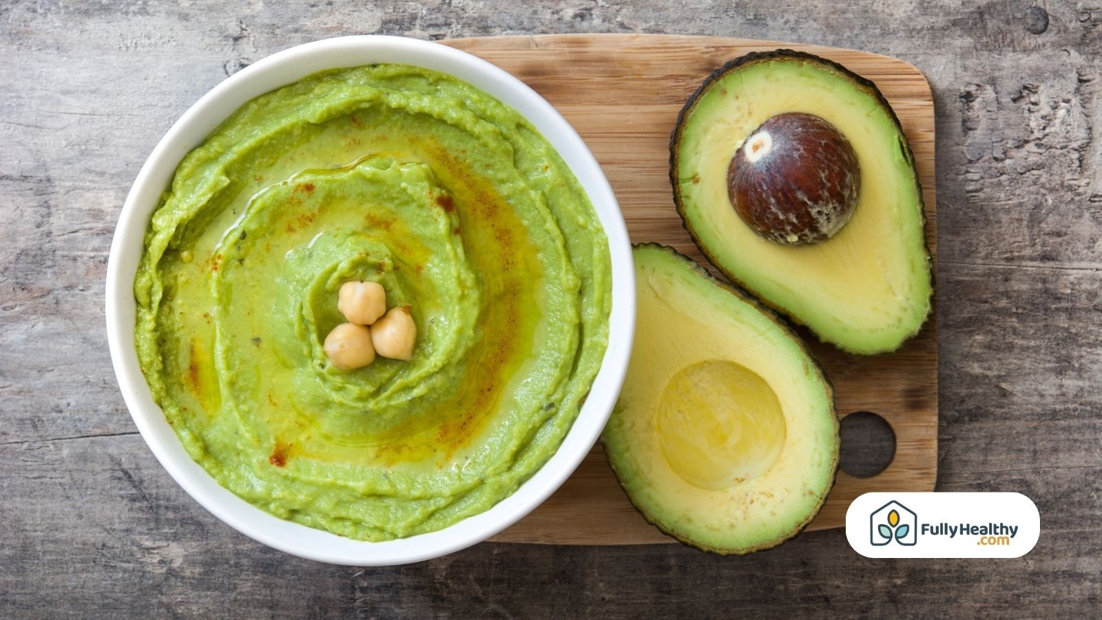 Bowl of avocado hummus with chickpeas and halved avocado