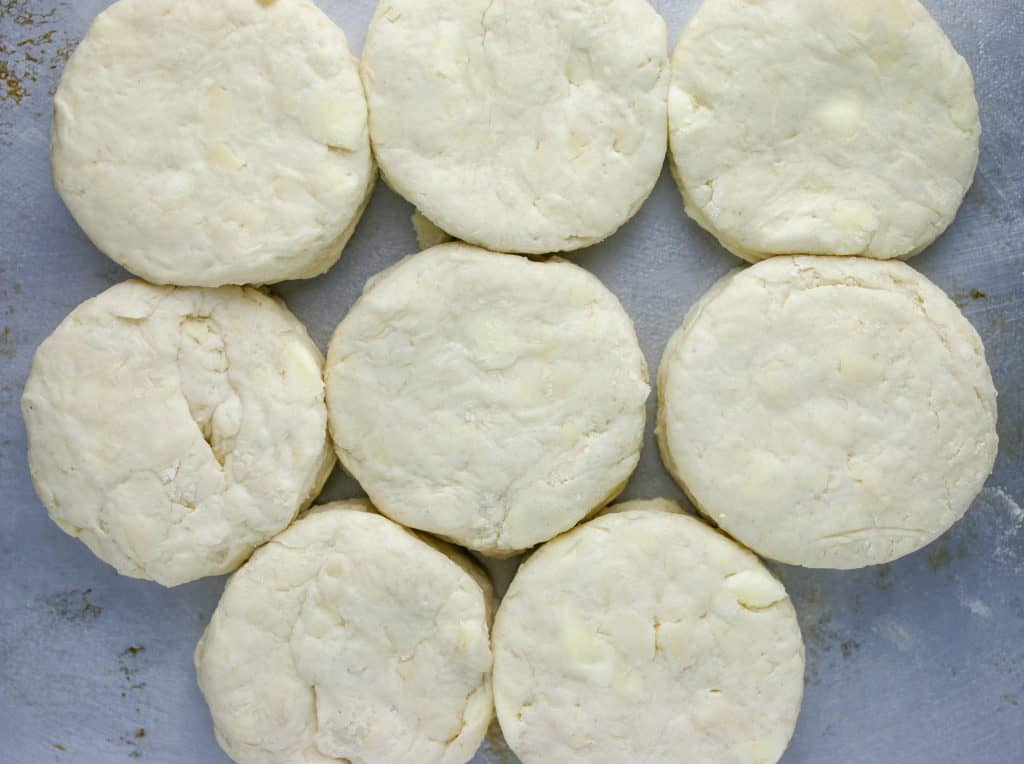 unbaked biscuits placed next to each other on a baking sheet with parchment paper