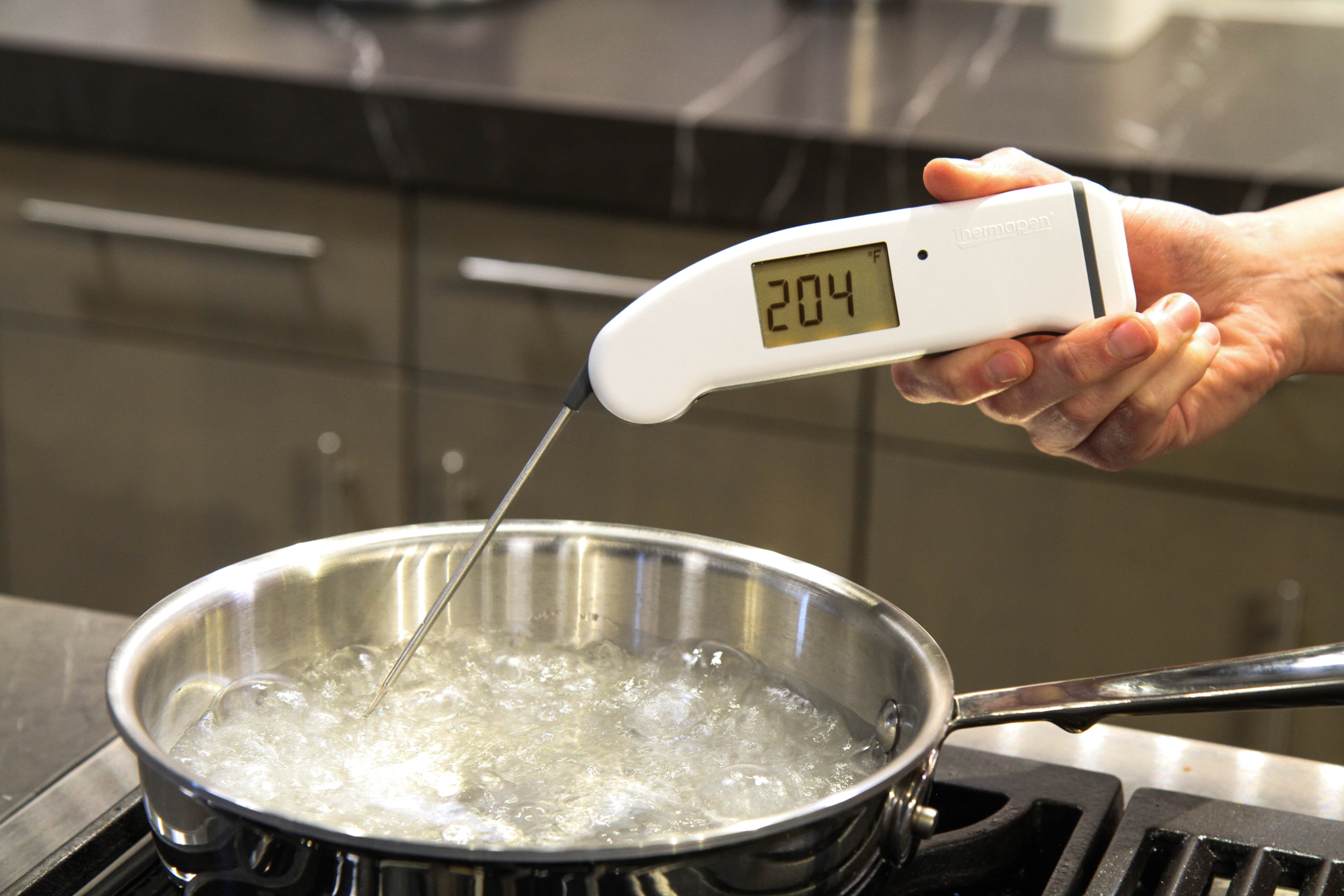 A digital thermometer being used to measure the boiling point of water