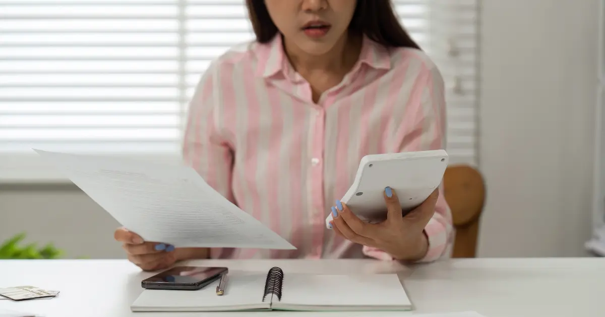 Creator reviewing earnings and calculator while researching do OnlyFans models pay taxes and IRS rules.