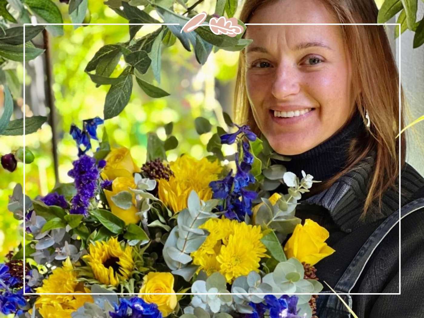 Woman smiling while holding a bouquet of yellow and purple flowers - Fabulous Flowers and Gifts