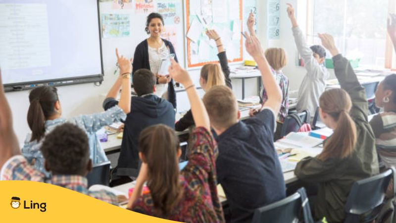 Rear view of teenage students raising hands in classroom - How To Be A Good Language Teacher