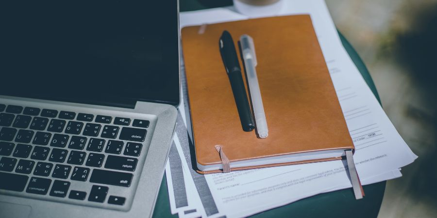 Planner and pens on table with laptop