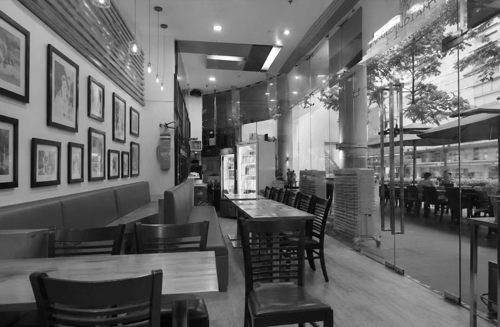 Welcoming interior of Anglo Indian Café & Bar featuring wooden furniture, large windows, and a bright dining atmosphere.