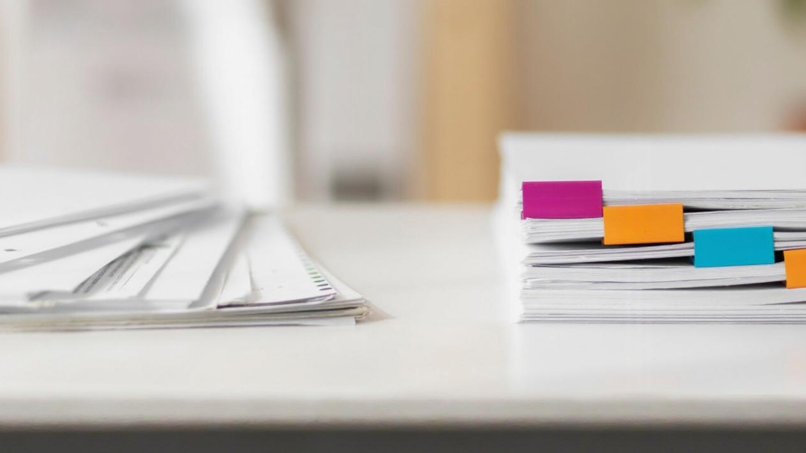 Two document stacks on a desk, one organized with colorful tabs, representing the difference between sales collateral and outbound marketing tools.