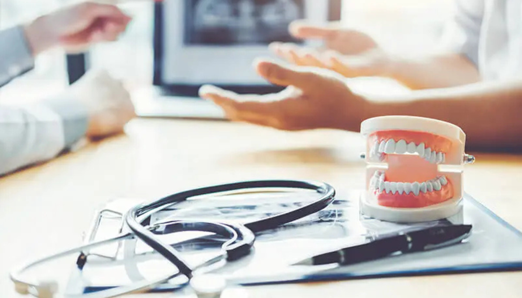 Tannmodell med stetoskop ved siden av skjerm som viser tannrøntgen.