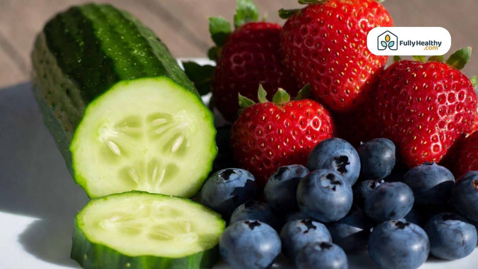 Sliced cucumber with strawberries and blueberries on a plate.