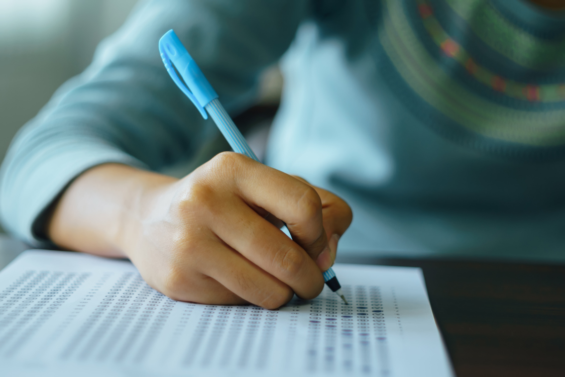Close-up of a Filipino student filling out a test form, representing candidate screening and qualifications.