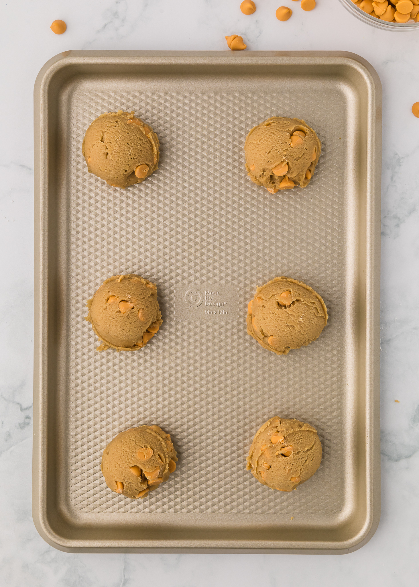 six unbaked butterscotch cookie dough balls on a baking sheet