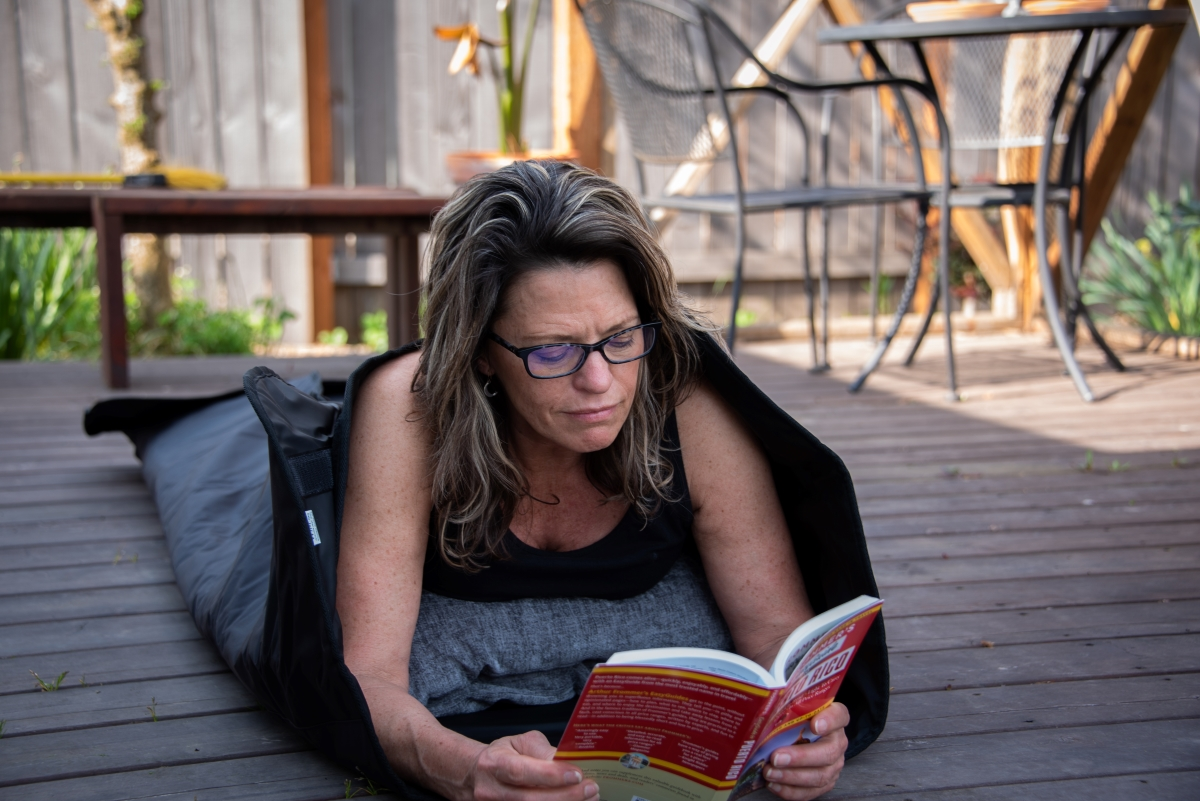 Lady reading outside in a far infrared sauna blanket