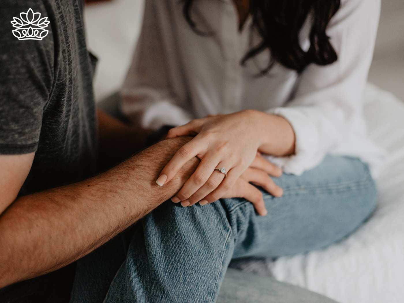 Close-up of a couple holding hands, featuring an engagement ring, symbolising commitment and affection in a casual, intimate setting. Fabulous Flowers and Gifts. Delivered with Heart.