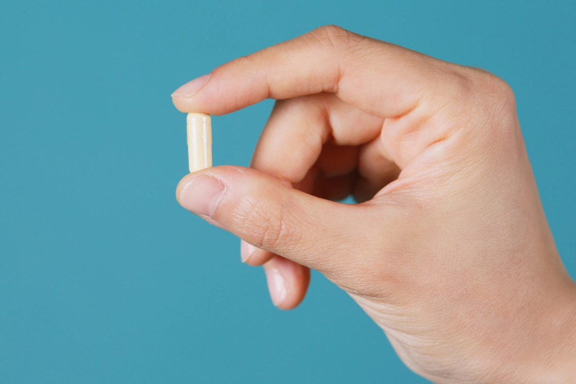 A hand holds a small, beige custom supplement.
