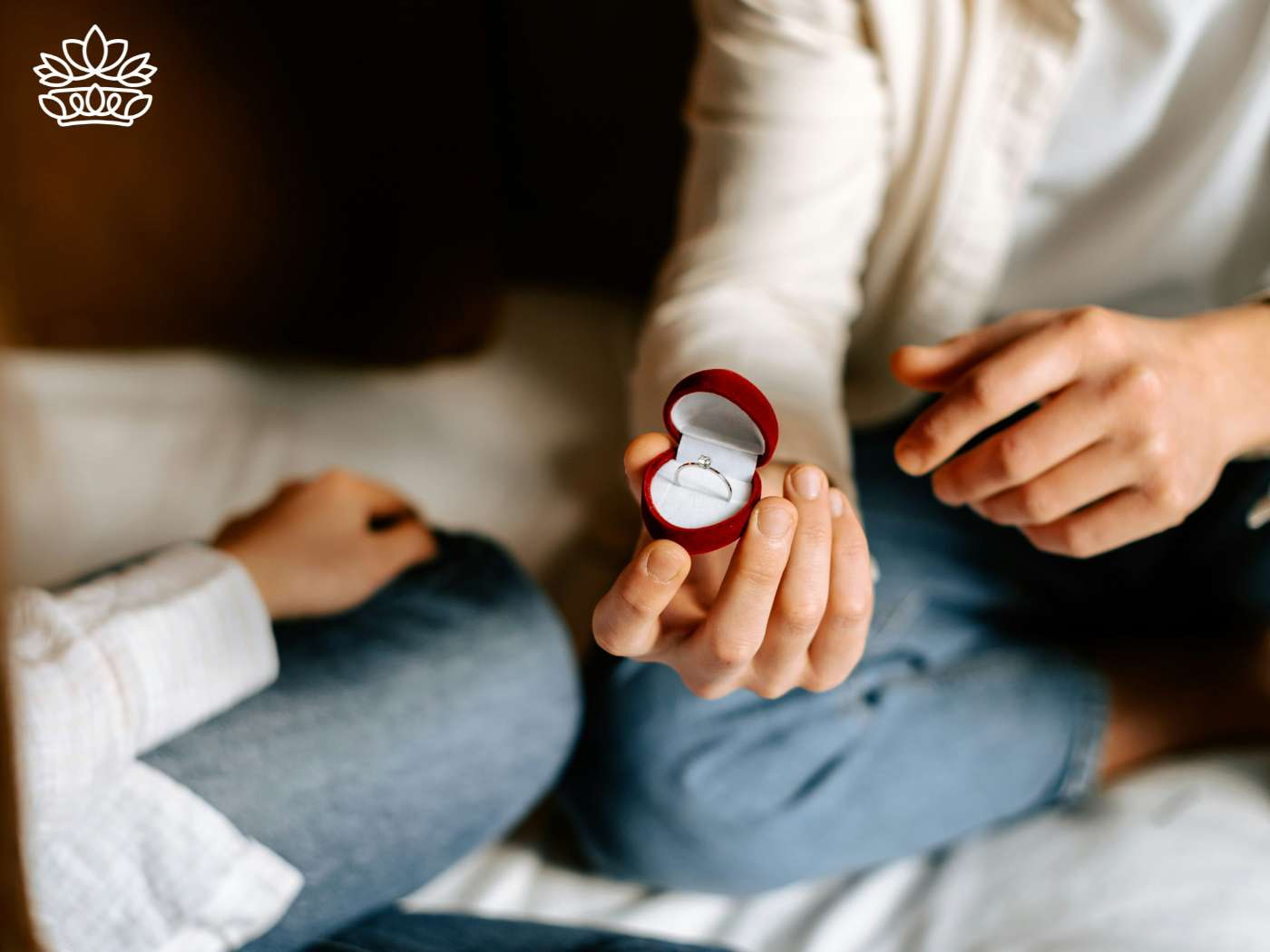 A tender moment captured as a person presents an open engagement ring box with a sparkling ring to their partner, symbolizing a proposal. This intimate gesture is highlighted by the Engagement Gift Boxes Collection from Fabulous Flowers and Gifts, designed to enhance such significant life events.